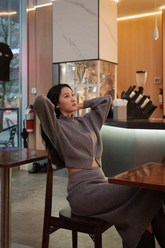 a lady in a crop zip up cardigan and a grey skirt